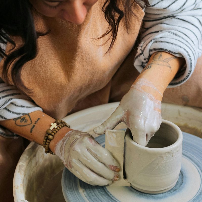 Potter shaping a cup on the wheel