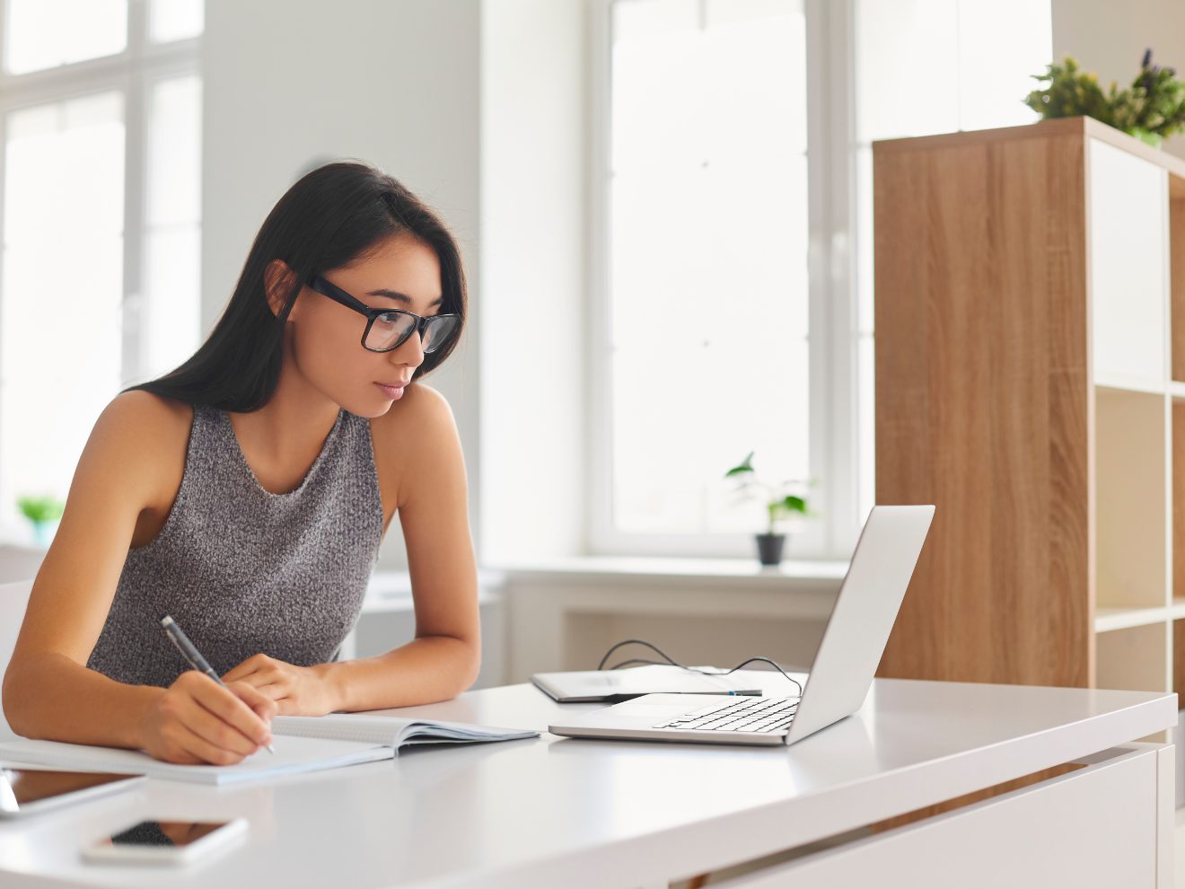 Woman studying at her laptop in a bright room